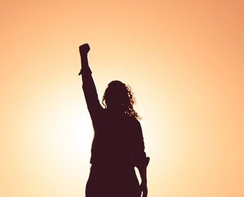 Une femme le poing levé devant le Soleil.