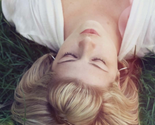 Une femme au visage apaisé allongée dans l'herbe